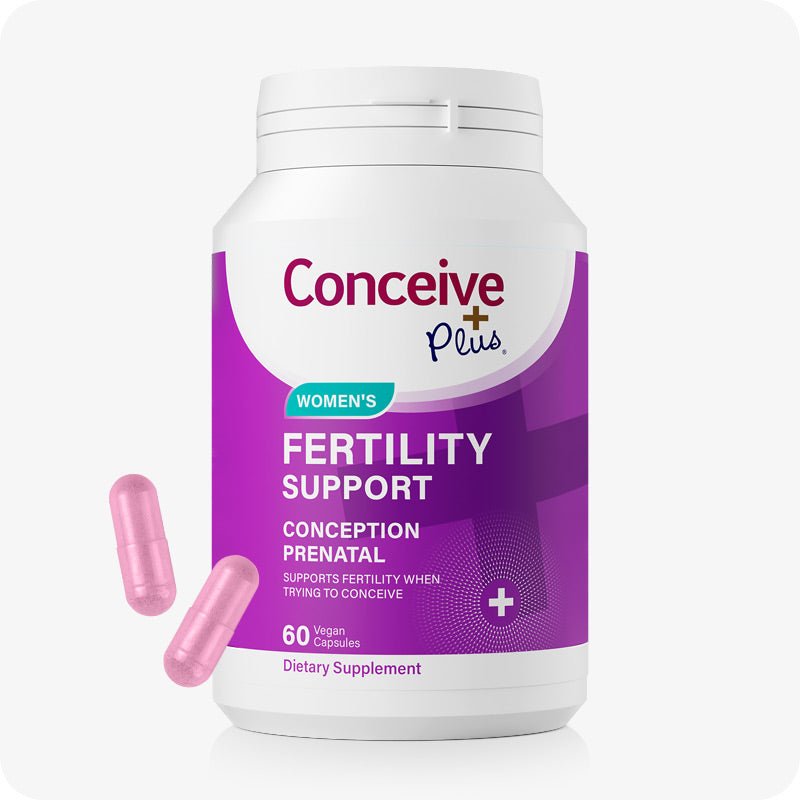 Front Image of the Conceive Plus Women Fertility Support US Bottle on a white background with two pink capsule at the lower left corner. The bottle purple and white label with white text.